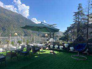 a patio with a table and chairs and an umbrella at Hotel Gandhi's Paradise in Dharamshala