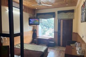 ein Schlafzimmer mit einem Etagenbett, einem TV und einem Schreibtisch in der Unterkunft Hotel Gandhi's Paradise in Dharamshala