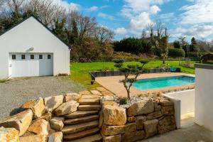 a house with a stone wall next to a swimming pool at Villa Ti Vakansou - Avec piscine privée in Clohars-Carnoët