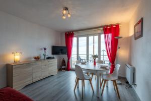 sala de estar con mesa de comedor y cortinas rojas en Face à la Mer - Appt vue mer, en Mers-les-Bains