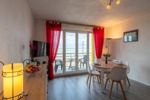 cocina y comedor con mesa y cortinas rojas en Face à la Mer - Appt vue mer, en Mers-les-Bains