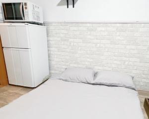 Łóżko w pokoju z kuchenką mikrofalową i lodówką w obiekcie 高田馬場駅4分4人可303 w Tokio