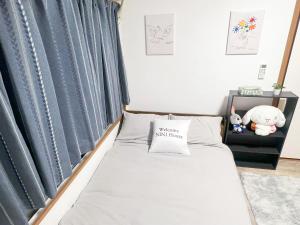 małe łóżko w pokoju z niebieskimi zasłonami w obiekcie 高田馬場駅4分4人可303 w Tokio