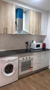 eine Küche mit Waschmaschine und Mikrowelle in der Unterkunft Meta Habitat Ramon Lujan A in Madrid