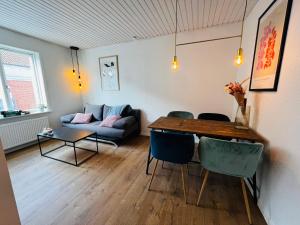 The Old Hotel Silkeborg - 1MTH في سيلكبورج: غرفة معيشة مع طاولة وكراسي وأريكة