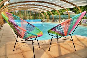 2 sillas coloridas sentadas junto a una piscina en Domaine de Lestroué - Île d'arz, en La Vraie-Croix