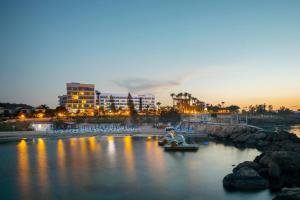 a harbor with boats in the water at night at Cavo Maris Beach Hotel in Protaras