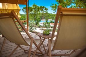 two chairs and a table on a deck at Arena One 99 Glamping in Pula