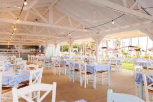 un salón de banquetes con mesas blancas y sillas blancas en Cavo Maris Beach Hotel, en Protaras