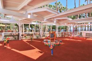 uma área de lazer com baloiços e um parque infantil em Cavo Maris Beach Hotel em Protaras