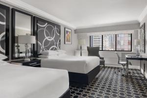 Habitación de hotel con 2 camas y escritorio en The Muse New York, en Nueva York