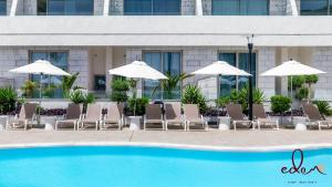 a group of chairs and umbrellas next to a pool at סוויטה מעוצבת עם מרפסת ליד הים - By Edomlux in Eilat