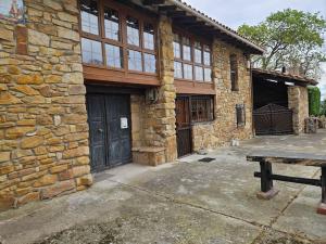 a stone building with a wooden door and a bench at 14A09 Casa de la Capilla in Colunga