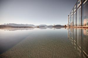 un bâtiment en verre sur un lac avec réflexion dans l'établissement Saltus, à San Genesio Atesino