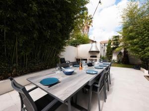 Villa Paradis - climatisation et piscine في مونبلييه: طاولة خشبية طويلة مع لوحات وكراسي زرقاء