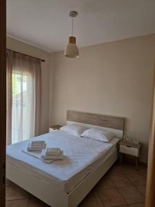 a bedroom with a bed with white sheets and a window at Villa Keramidi in Limenaria