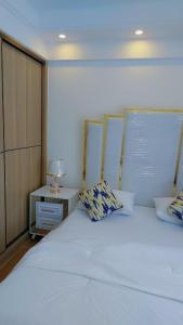 a bedroom with a large white bed and a night stand at Luxury Apartment Lavington in Mutomo