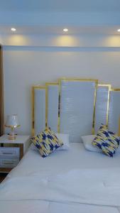 Luxury Apartment Lavington في Mutomo: سرير أبيض مع وسادتين ومصباح على طاولة