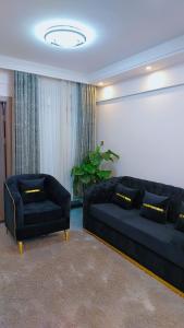 a living room with a black couch and a chair at Luxury Apartment Lavington in Mutomo