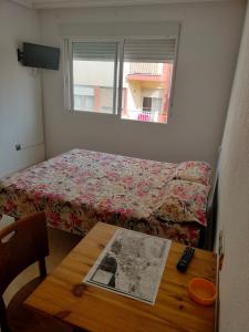 Un pequeño dormitorio con una cama y una mesa con un periódico. en HOLIDAY CENTRE DELUXE, en Alicante