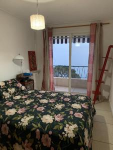- une chambre avec un lit doté d'un couvre-lit floral et d'une fenêtre dans l'établissement Le Bleu, à Roquebrune-Cap-Martin