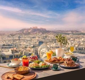 een tafel met borden eten bovenop een stad bij St George Lycabettus Lifestyle Hotel in Athene
