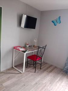 a desk with a chair and a tv on a wall at maison ancienne in Louviers