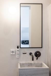 a bathroom with a sink and a mirror at aníko suites White Alley in Mýkonos City