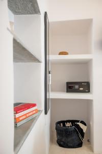 a book shelf with a clock and a basket of books at aníko suites White Alley in Mýkonos City