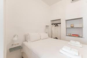 a white bedroom with a white bed and a mirror at aníko suites White Alley in Mikonos