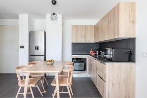 a kitchen with a table and chairs and a refrigerator at Appartement Vue Mer 50m plage des Salins Piscine 2 parkings Terrasse in Hyères