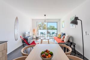 a living room with a table with a bowl of fruit on it at Appartement Vue Mer 50m plage des Salins Piscine 2 parkings Terrasse in Hyères +15 photos