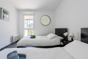 a bedroom with two beds and a mirror on the wall at Appartement Vue Mer 50m plage des Salins Piscine 2 parkings Terrasse in Hyères