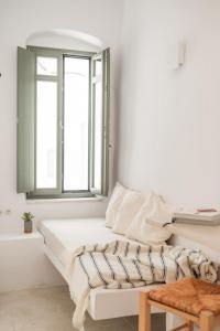 a white room with a bed and a window at aníko suites White Alley in Mýkonos City