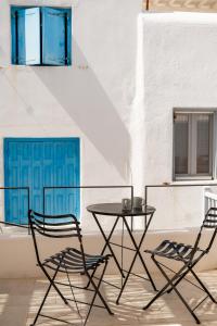 two chairs and a table and a blue door at aníko suites White Alley in Mikonos