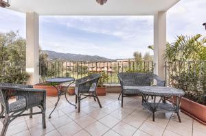 a patio with chairs and tables on a balcony at Stunning Villa Paola with Swimming Pool & Terrace! in Villasimius