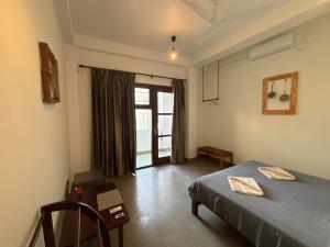 een slaapkamer met een bed, een tafel en een raam bij Mirage Beach House at Morava Court in Hikkaduwa
