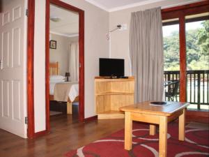 a room with a bedroom with a bed and a table at Port St Johns River Lodge in Port St Johns