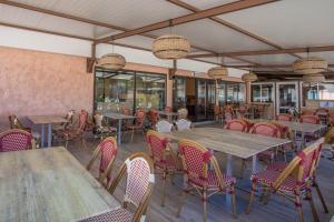 un restaurante con mesas y sillas de madera y ventanas en Mobil home vacances en Puget-sur Argens