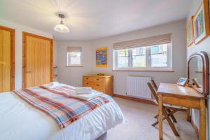 a bedroom with a bed and a desk and windows at 7 The Old Woodyard in Kendal