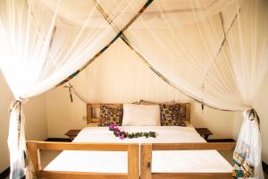 a bed in a tent with flowers on it at Villa Katwe in Masaka
