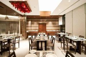 Hotel tu casa International Near Delhi Airport في نيودلهي: غرفة طعام مع طاولات وكراسي في مطعم