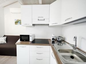 een keuken met witte kasten en een wastafel bij Affittimoderni Castelsardo Il Sole - CSSO11 in Castelsardo