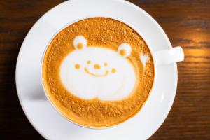 una tazza di caffè con una faccina sorridente disegnata sopra di PAYSAGE MORIGUCHI a Mima