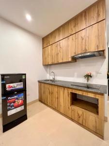 a kitchen with wooden cabinets and a sink and a refrigerator at NINE HOUSING 290 Kim Ma in Hanoi