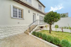 a house with stairs and a tree in the yard at Chic and modern house with parking garden and gym in Saint-Denis