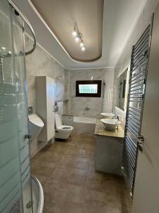 a bathroom with a toilet and two sinks and a shower at Summerhouse in Nea Karvali +6 photos