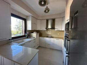 a kitchen with white cabinets and a large window at Summerhouse in Nea Karvali