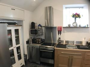 a kitchen with a stove and a sink and a microwave at Charming 1-Bed Barn Alton Towers Polar Bears Peaks in Whiston