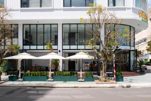 a building with tables and umbrellas in front of it at PĀMA Boutique Hotel & Bistro in Da Nang